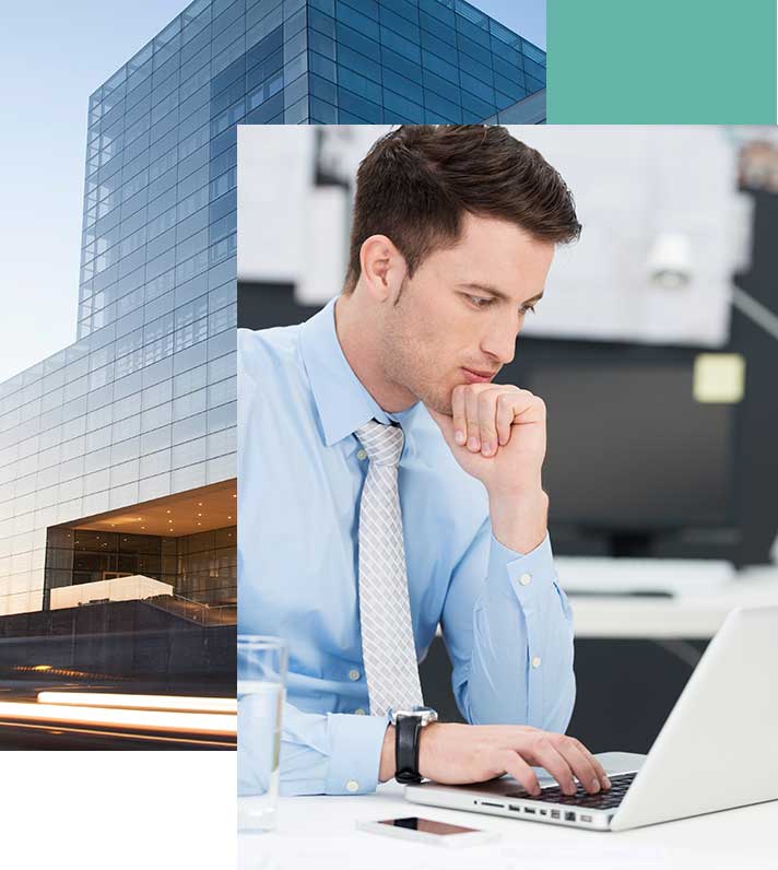 Man looking at laptop with a building background